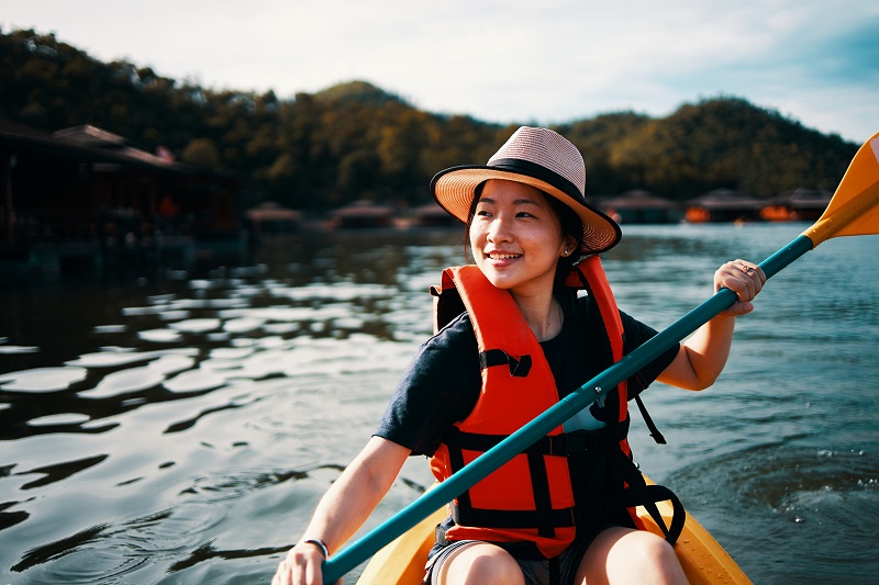 Asian girl is using action camera while kayaking at Kanchanaburi, Thailand.